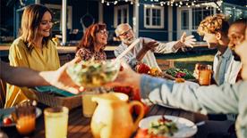 Many people sit around a dining table outdoors to each together