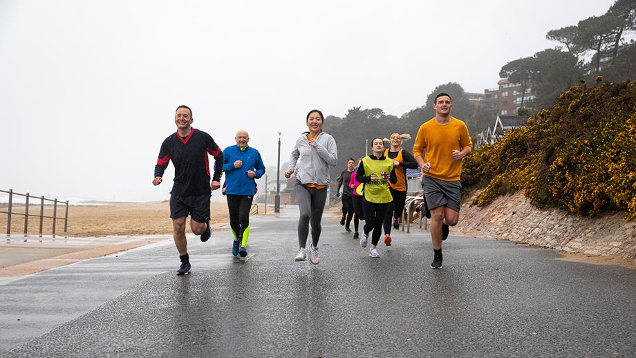 A group of men and women are running along a promenade for their Mayday Mile.