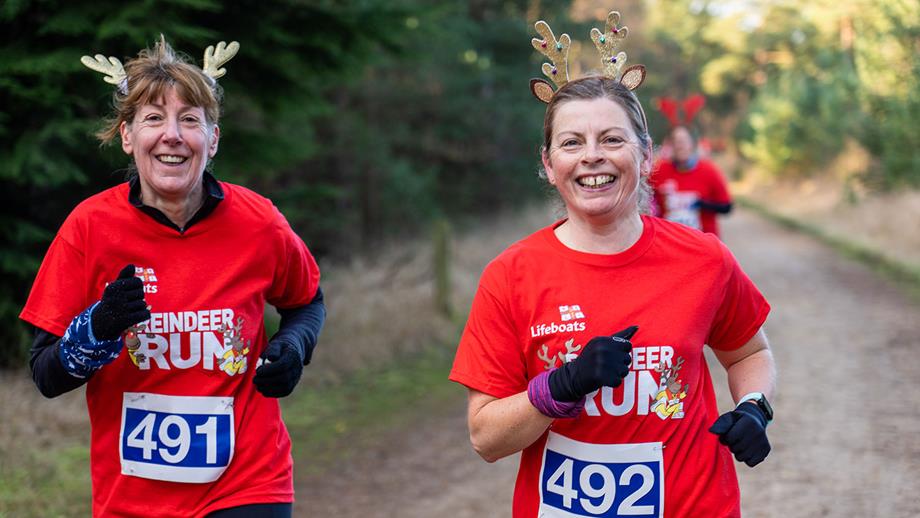 Two smiling runners set a steady pace while taking part in an RNLI Reindeer Run