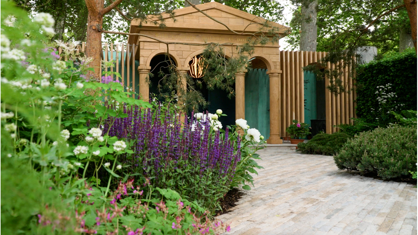The RNLI’s garden at the RHS Chelsea Flower Show. There are lots of green plants with purple and white flowers and a pavilion at the back.