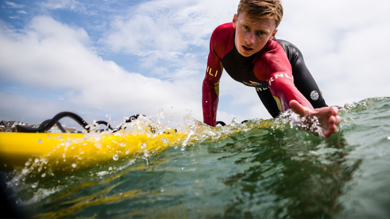 Boscombe lifeguard James Wheeler on a rescue board reaching down towards the camera