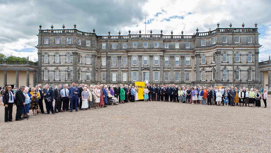 Lots of RNLI volunteers stand outside a manor house in Scotland celebrating their long service