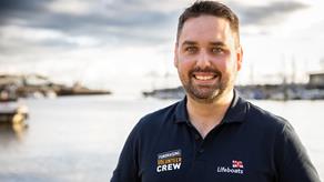 Fundraising Volunteer Cian Mathews standing by a bay wearing his fundraising volunteer crew polo shirt