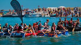 Three teams taking part in a raft race on the water.