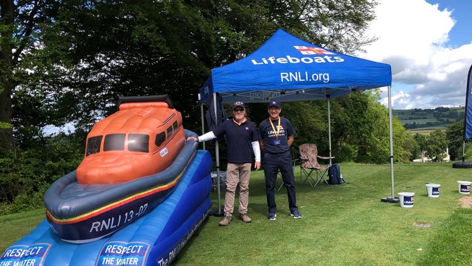 RNLI fundraisers stand under a gazebo next to an inflatable lifeboat while raising funds for Exmouth lifeboat station for their golf day