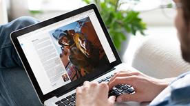 A person sat down using a laptop looking at induction pack materials online