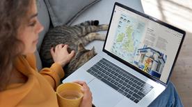 A person sat down using a laptop looking at induction pack materials online