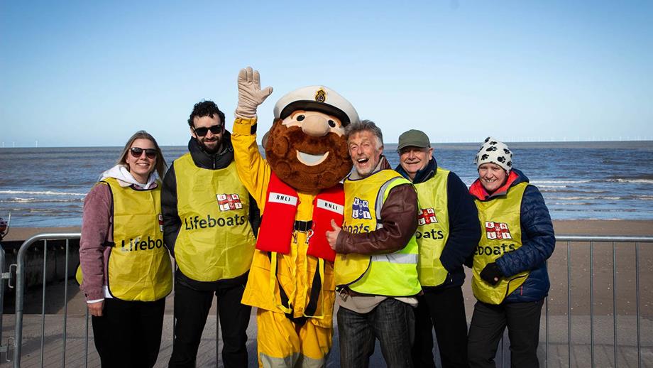 RNLI mascot Stormy Stan stood with Rhyl Dewi Sant dip event volunteers