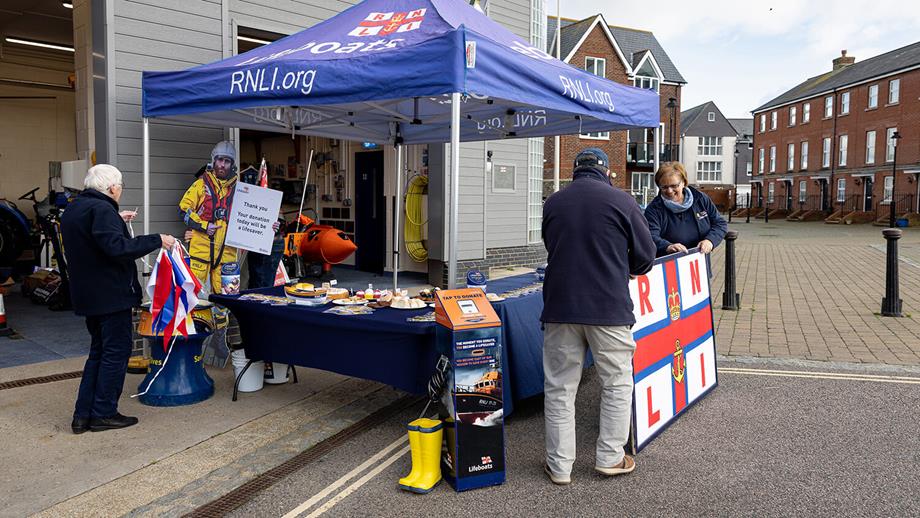 RNLI fundraising volunteers setting up a cake sale stall outside a lifeboat station