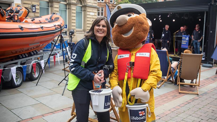 A fundraising volunteer standing next to Stormy Stan, the RNLI mascot.