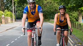 A male cyclist and a female cyclist, both in RNLI-branded clothing