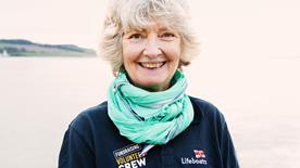 Close-up of a fundraising volunteer wearing an RNLI branded polo shirt and a light blue scarf.