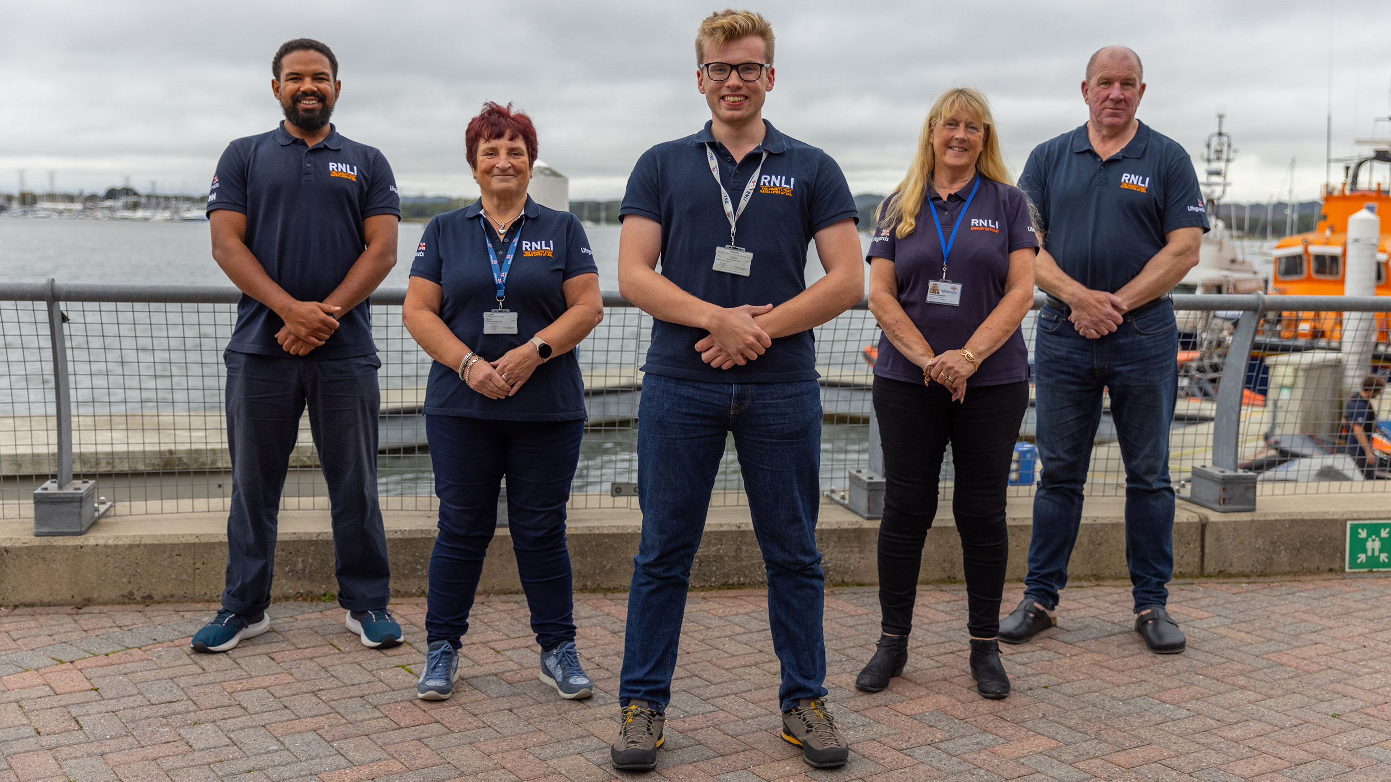 A group of RNLI volunteers stood on the pavement outside the RNLI College in Poole.