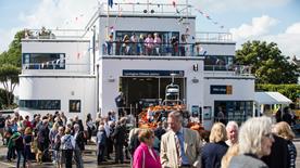 There are crowds of people in and around Lymington Lifeboat Station on a bright, sunny day.