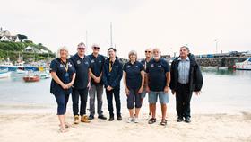 Group of RNLI fundraisers standing and smiling on a beach