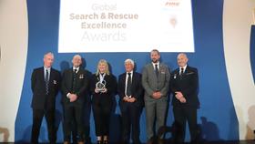 RNLI crew members in formal dress receiving an award at a presentation 