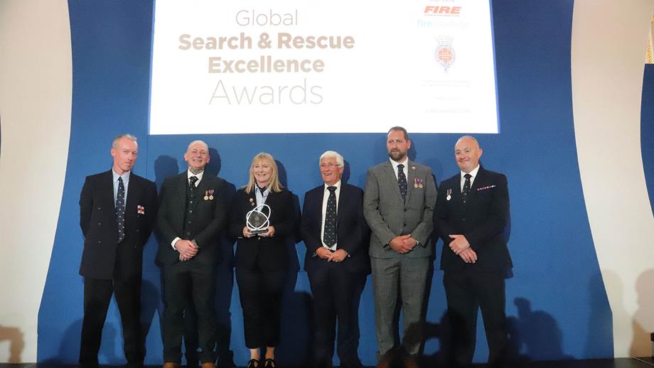 RNLI crew members in formal dress receiving an award at a presentation 