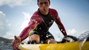 RNLI Lifeguard Richard Evans reaching out to rescue someone on his rescue board