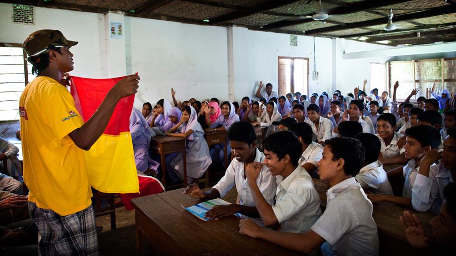 A lifeguard holding up a flag in a school water safety lesson in Cox’s Bazaar, Bangladesh