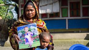 Rowshanara with her grandson, holding a photo of her granddaughter Shohagi who drowned outsideher home in Barisal