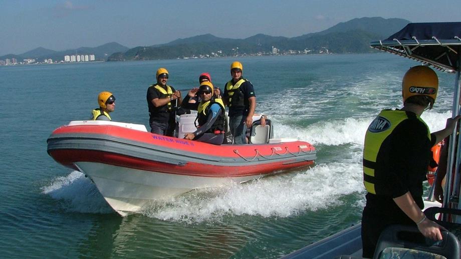 Maritime search and rescue training taking place in Brazil. A RIB lifeboat with five lifejacketed crew members onboard approaches another vessel as part of a training exercise.