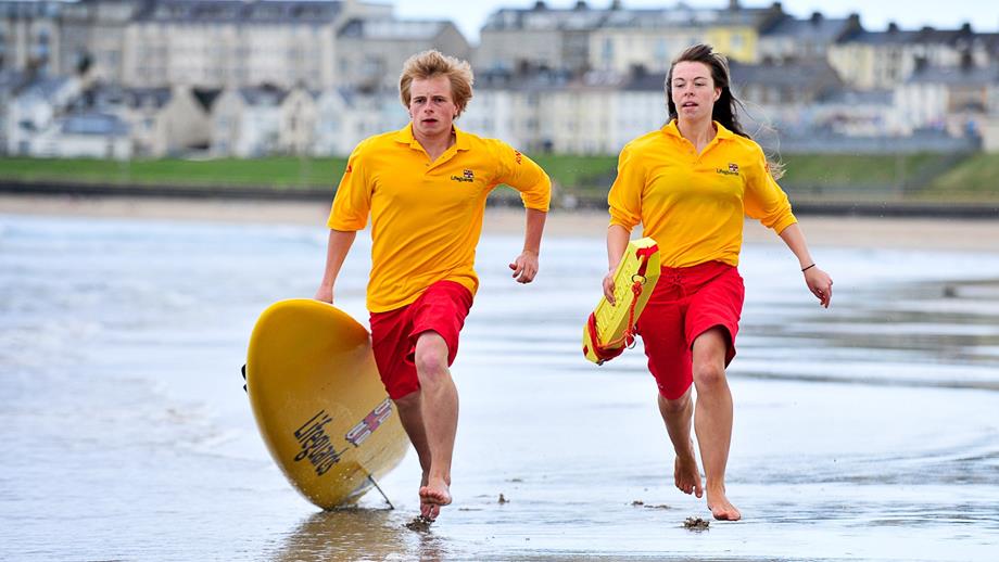 RNLI Lifeguards running along the beach in Portrush