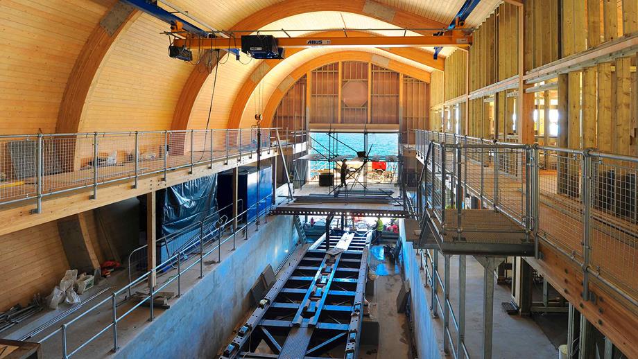 Interior view of a boathouse being constructed with wooden frame visible and scaffolding in place 
