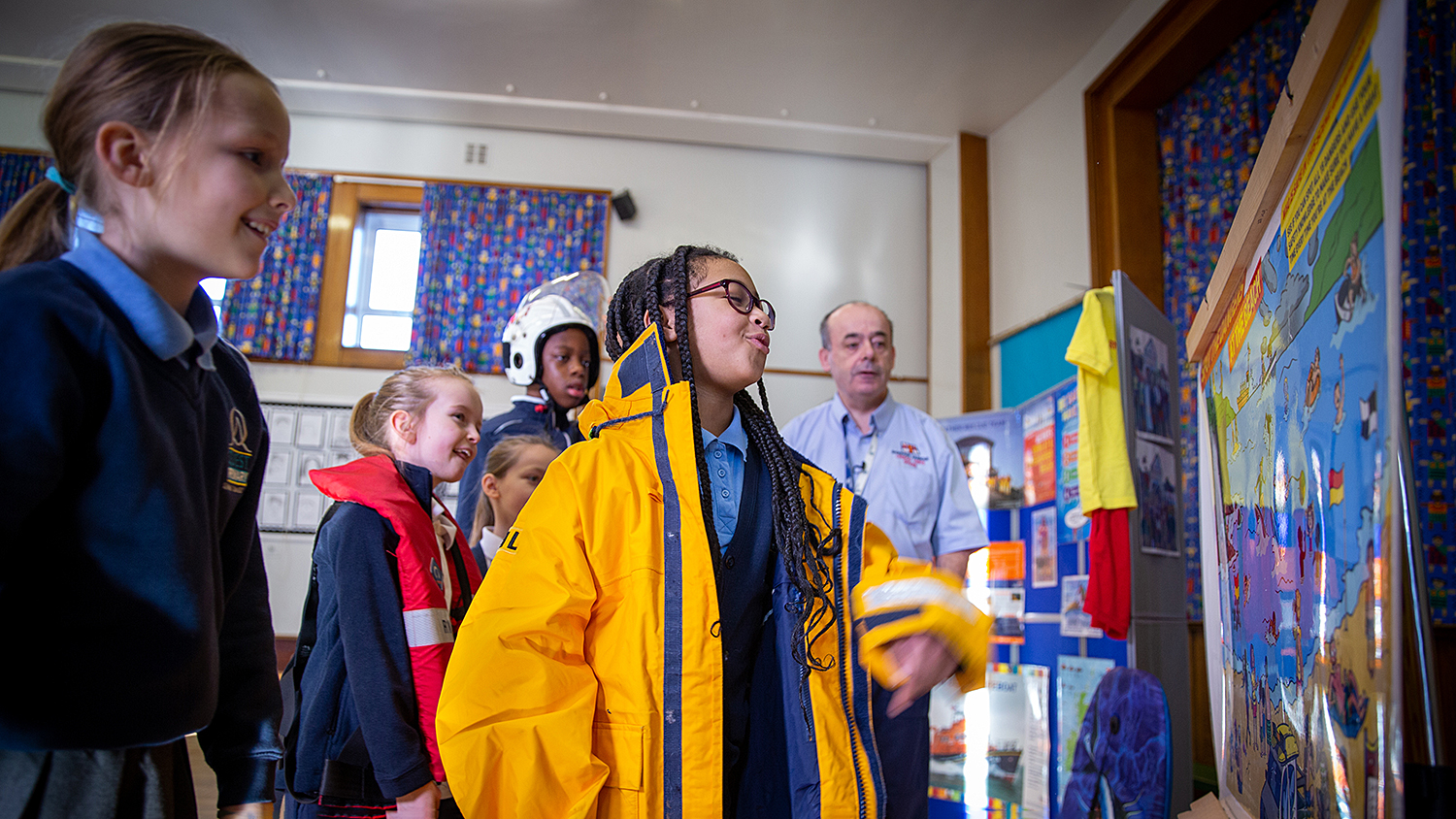 Children in a classroom looking at an RNLI poster