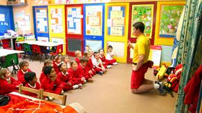 Young children in a classroom learning about water safety from an RNLI lifeguard