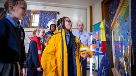 School children wearing different pieces of RNLI kit gathered round a spot the dangers board.
