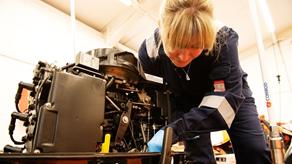 Cardigan Crew Member and Mechanic Sarah Morgan working on a D class lifeboat outboard engine in a workshop