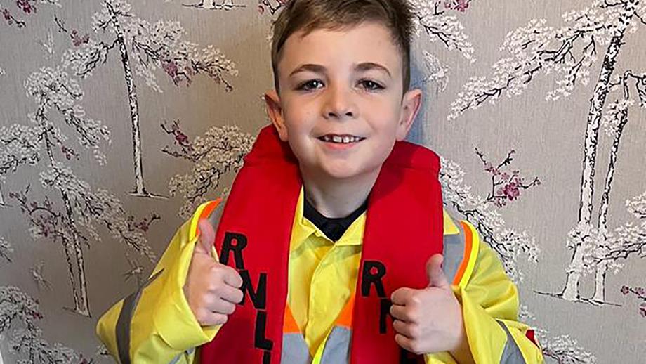 Henry, who is wearing an RNLI crew member costume, gives the camera a double thumbs up