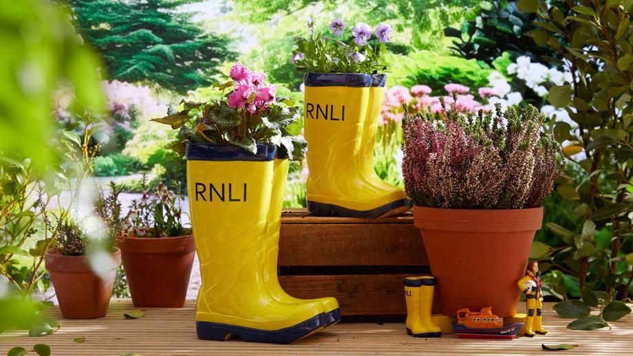 Ceramic RNLI yellow welly planters in a garden