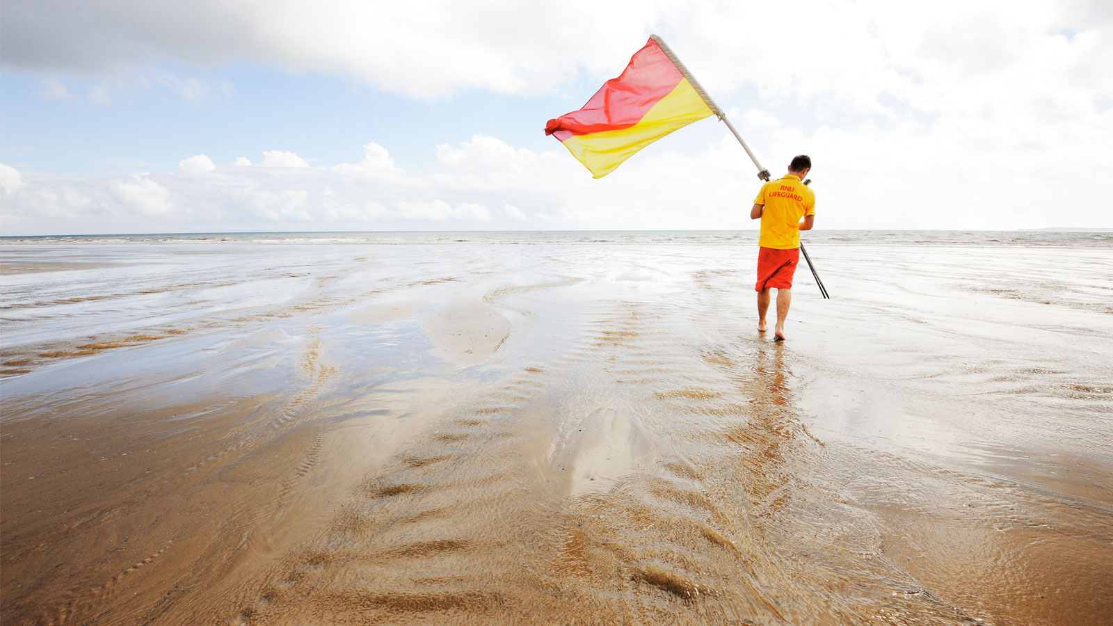 lifeguard putting out a beach flag