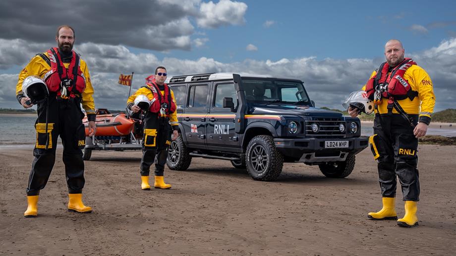Three crew members dressed in full kit stand on the beach