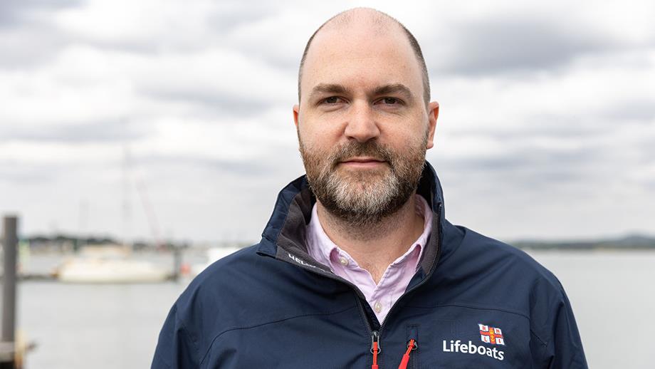 Rob Faricy, Safety and Independent Assurance Director at the RNLI. He is wearing a light pink shirt and a blue RNLI jacket. He is looking at the camera with a neutral expression.